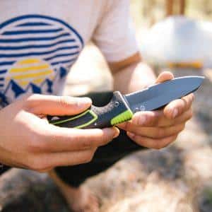 A person honing their survival knife skills in the woods.