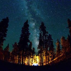 A starry sky illuminates a tent in the wilderness, emphasizing the need for survival skills.